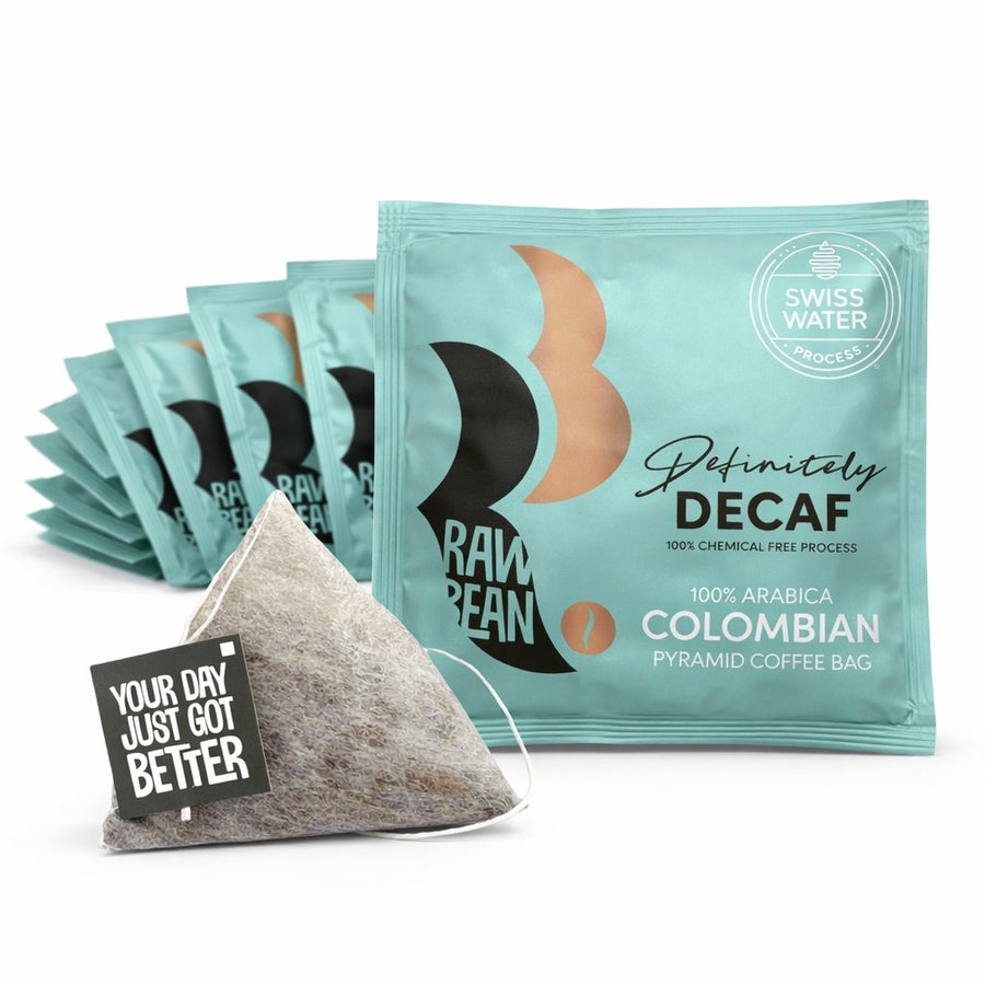 Individually wrapped Swiss Water decaf coffee bags beside a cream mug