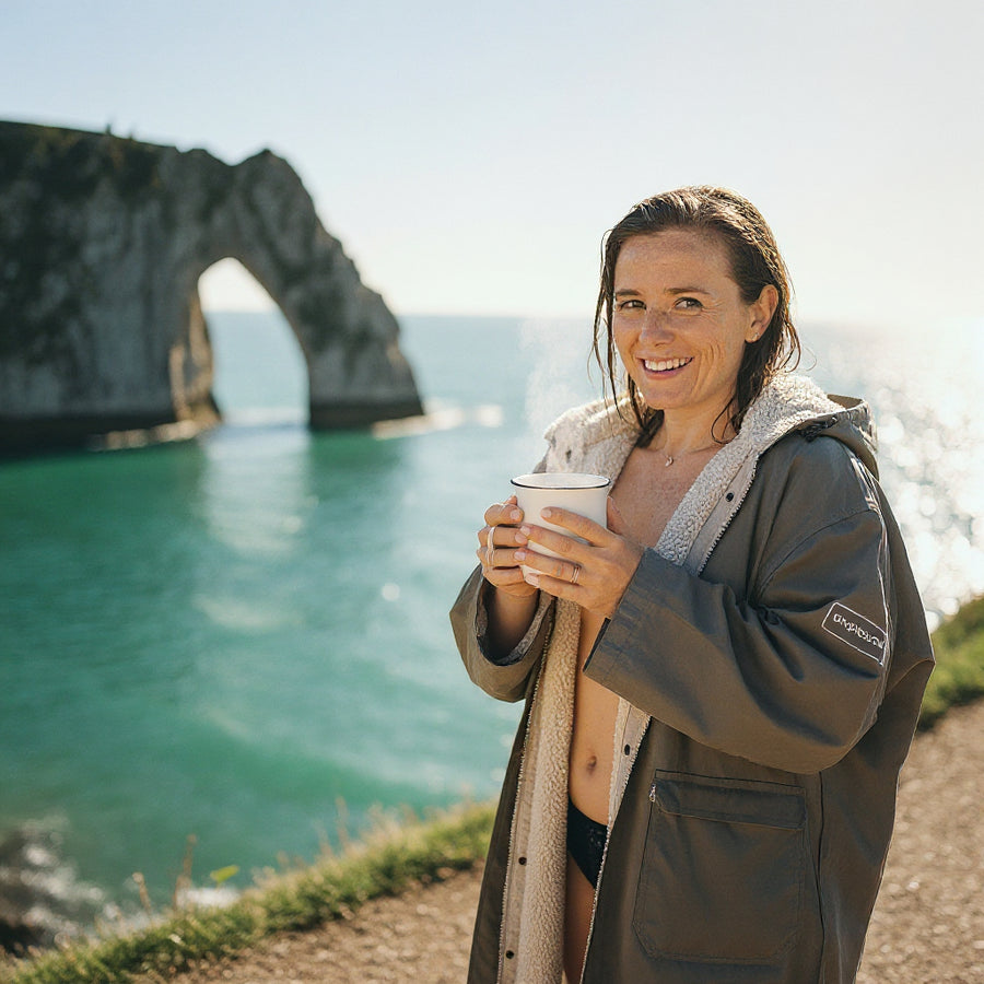 Wild swimmer in a change robe with a mug of Raw Bean coffee at Durdle Door