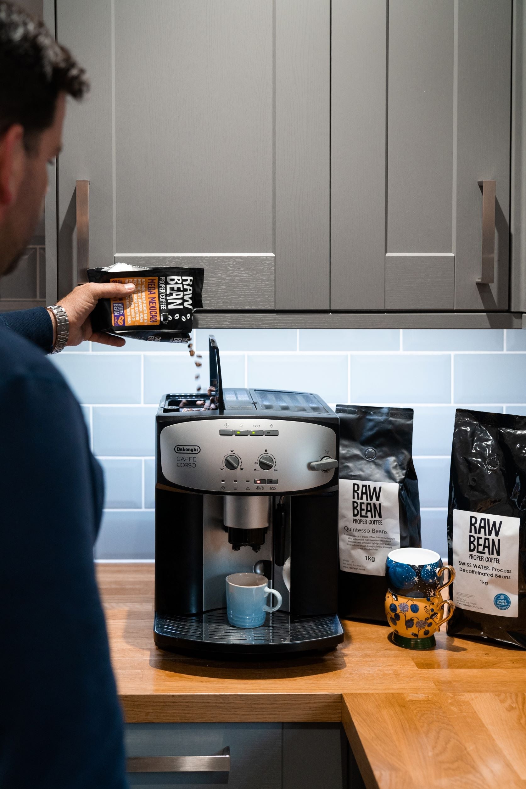 Meg Mexican beans being added to Delonghi Bean to cup machine, FInca Aurora, Swiss water Decaf 1kg bag on oak kitchen work top - 100% chemical free