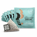 A Raw Bean Definitely Decaf pyramid coffee bag with tag and envelope, shown with our newly updated  envelope design. The new duck egg blue envelopes show the Swiss Water Decaf badge, Definitely Decaf 100% Arabica Colombian coffee.