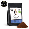 A matt black, pack of Peruvian Raw Bean Definitely Decaf, on a white background with a Great Taste Award badge and coffee grounds. The label shows certifications for Fairtrade, Organic and the 100% chemical free Swiss Water Process. Tasting Notes: Delicate spice, hint of walnut, medium fruity. Medium Roast. Strength 3, 200g.
