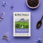 Birchall Virunga Earl Grey tea package on a purple background with a bowl of Earl Grey loose tea showing the cornflowers