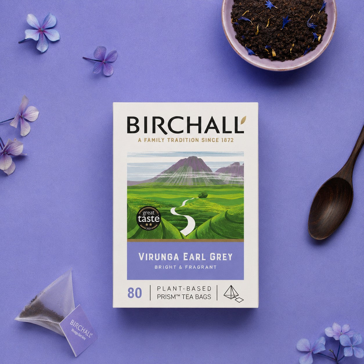 Birchall Virunga Earl Grey tea package on a purple background with a bowl of Earl Grey loose tea showing the cornflowers