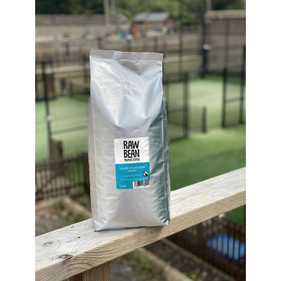 Raw Bean Unpacked Classic house blend part of the Waitrose Unpacked trial, pack shot on wooden ledge with Padel court in the background 